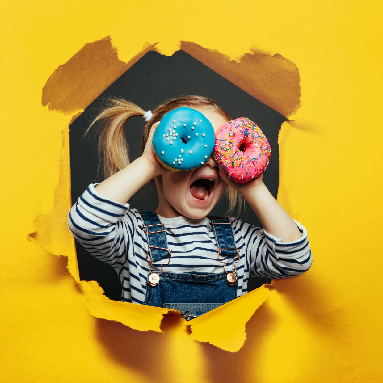 happy-cute-boy-is-having-fun-played-shwith-donuts-black-background-wall-scaled