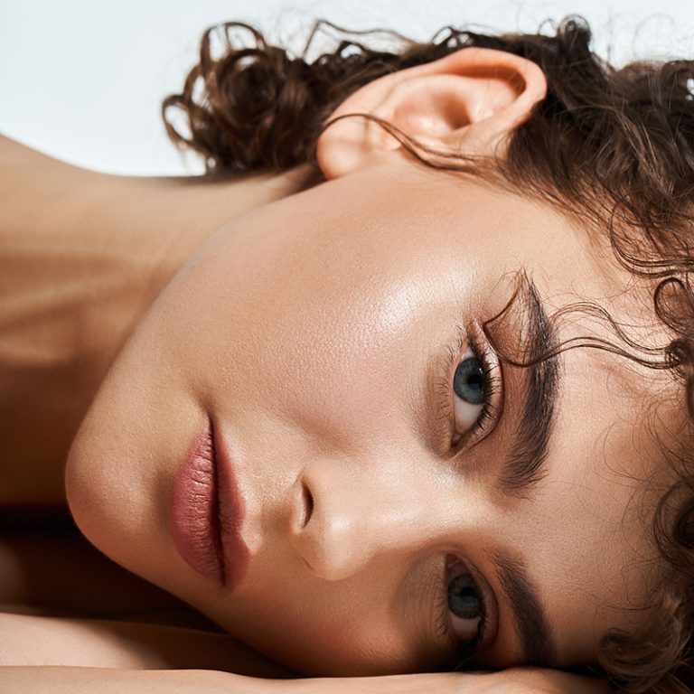 Radiant young woman rests her head on her arm, showcasing natura